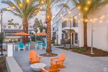 A patio with orange chairs and palm trees.